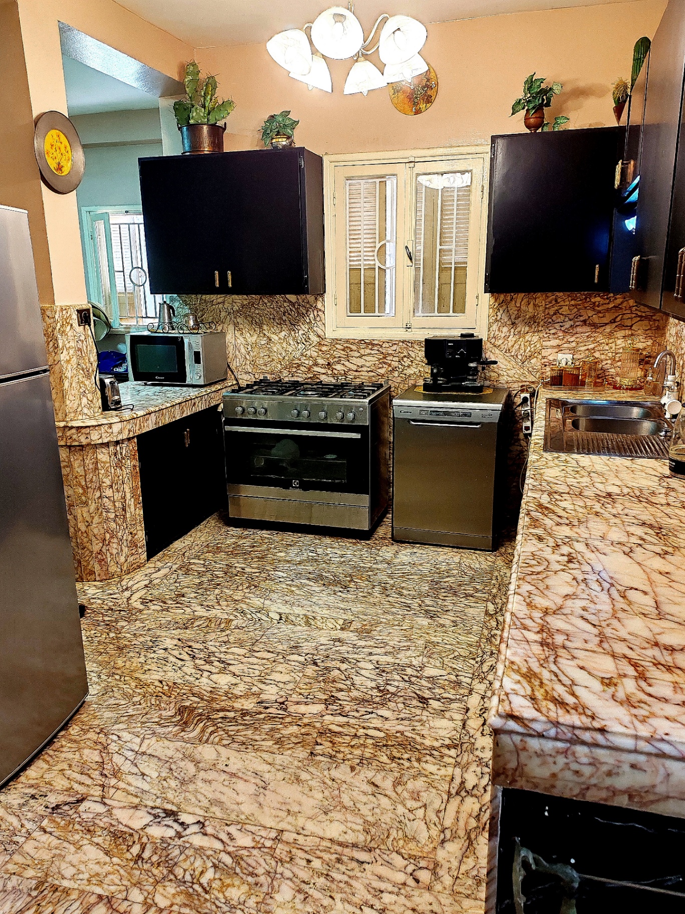 First-floor kitchen — marble floors and counters, dark cabinets and stainless-steel appliances